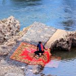 man cleaning carpet at river